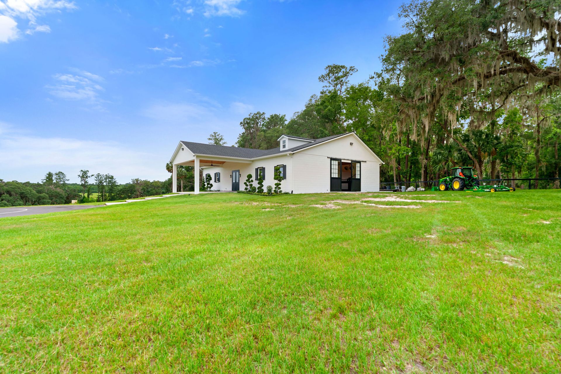 A white house is sitting on top of a lush green field.
