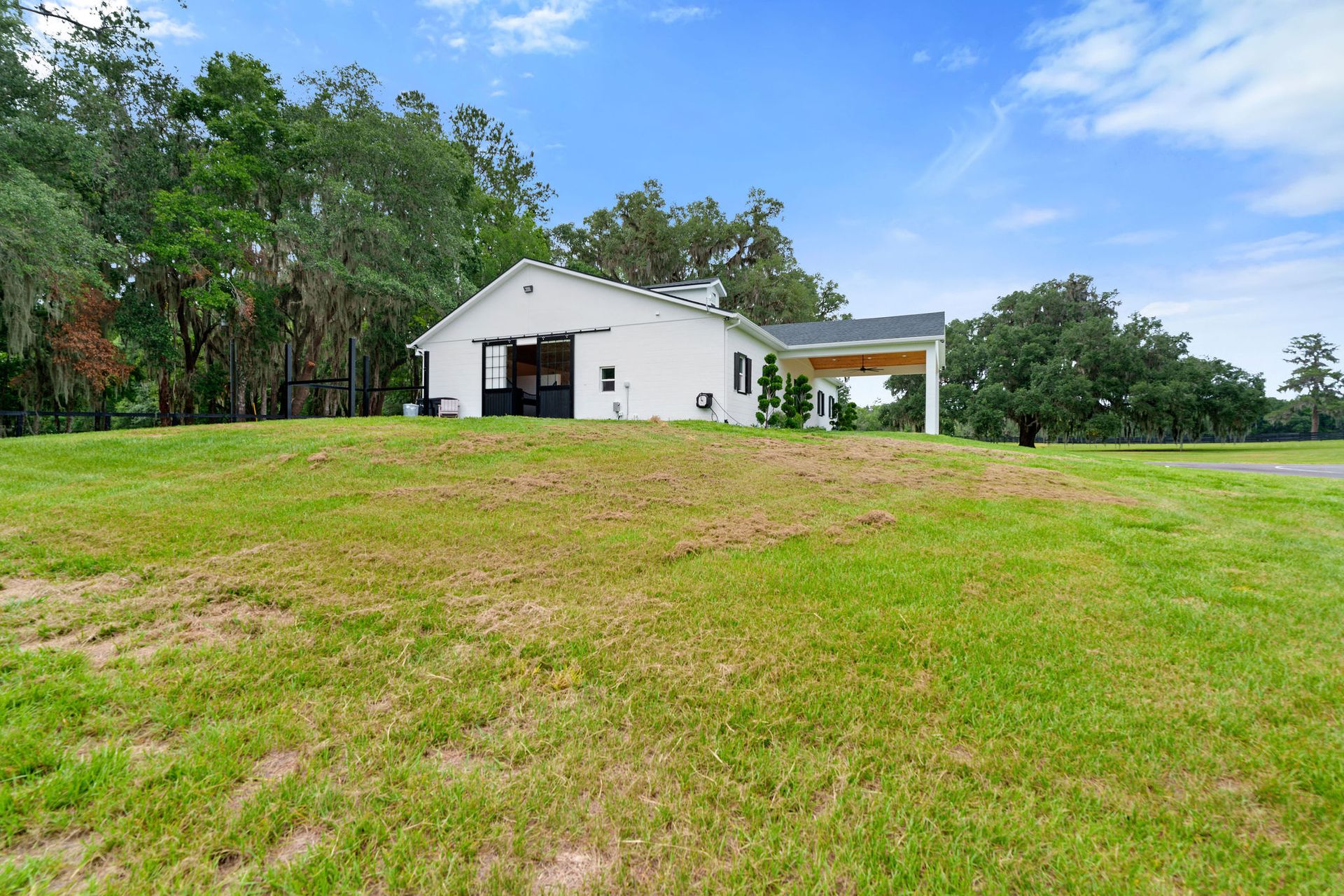A white barn is sitting on top of a lush green field.