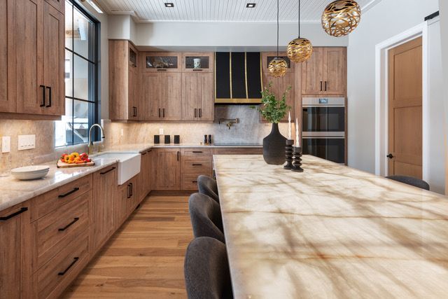 A kitchen with wooden cabinets and a marble counter top.