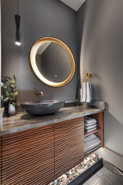A bathroom with a round mirror and a sink