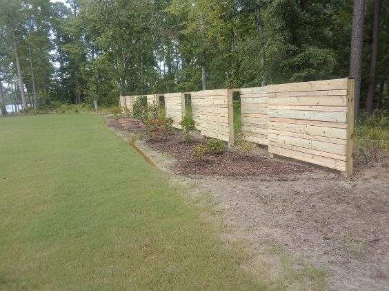 Wooden fence along a grassy field beside a wooded area