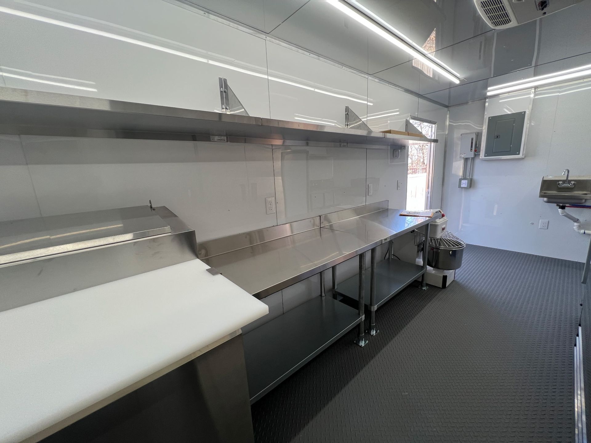 Modern mobile Food Kitchen interior Food Kitchen with stainless steel prep tables, white counters, bright overhead lighting.