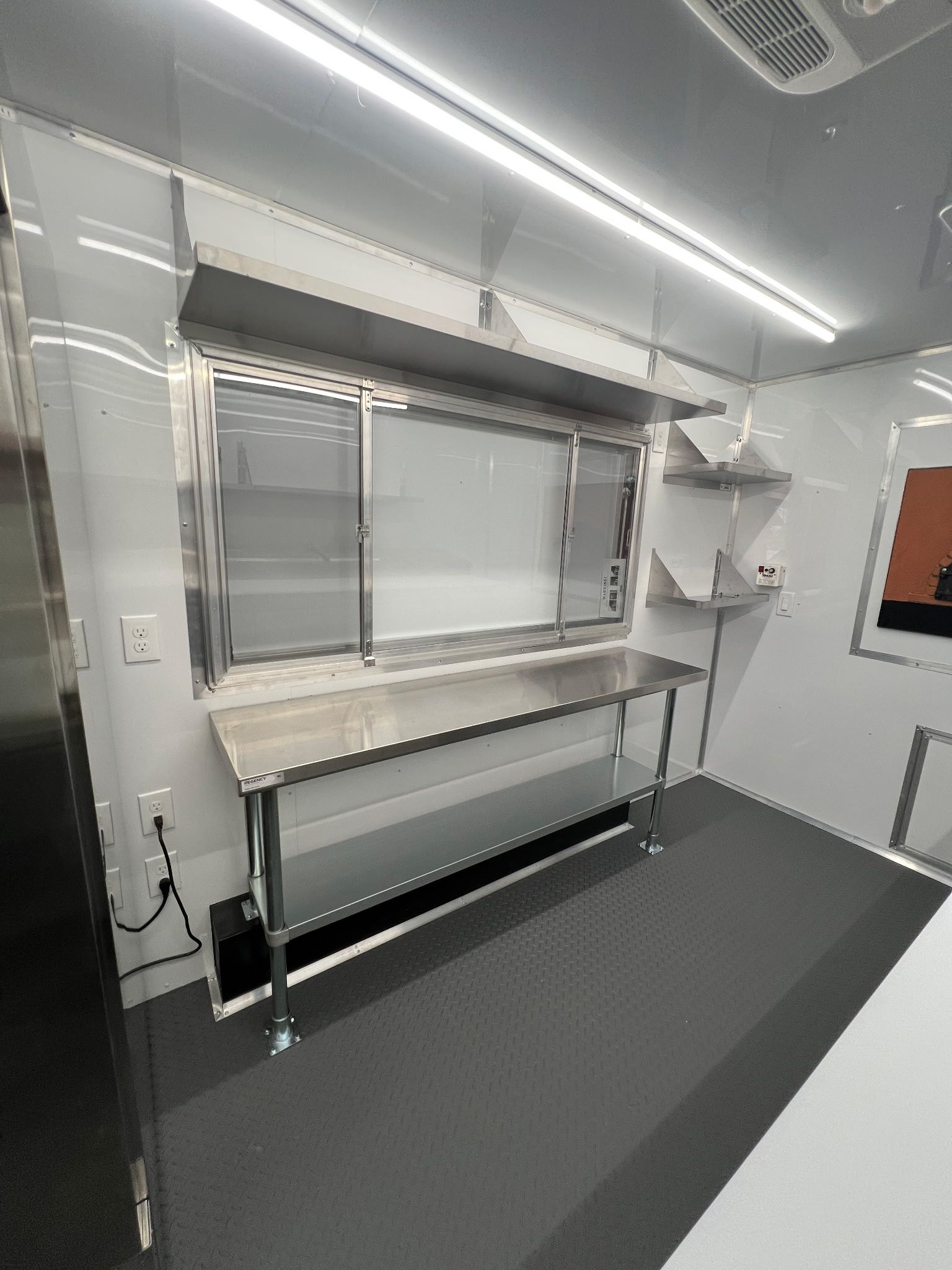 Interior of a small room with a fold-down bunk bed, window blinds, and gray flooring