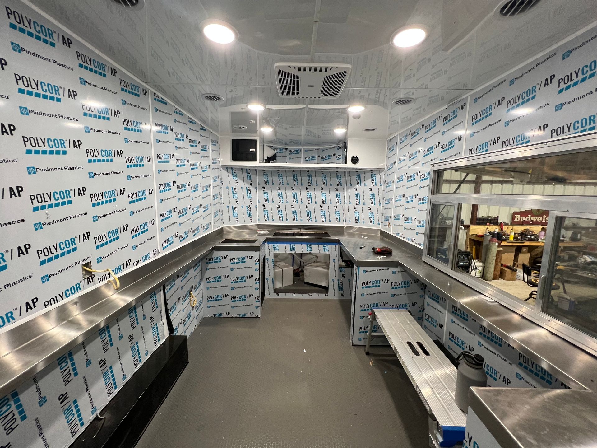 Interior of construction of mobile food trailer kitchen upgrade with stainless counters and a pass-through window