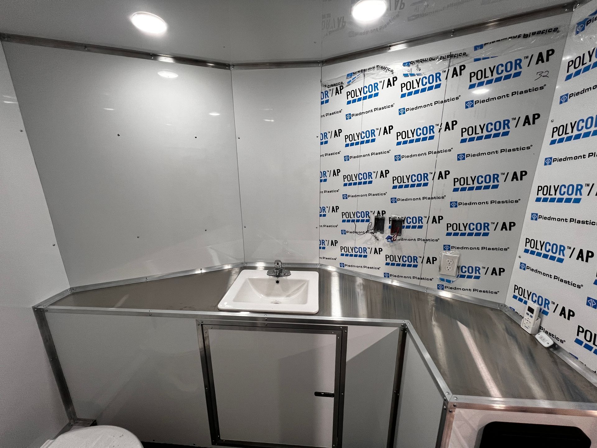 Stainless steel commercial kitchen prep sink area with unfinished walls and countertop protection panels