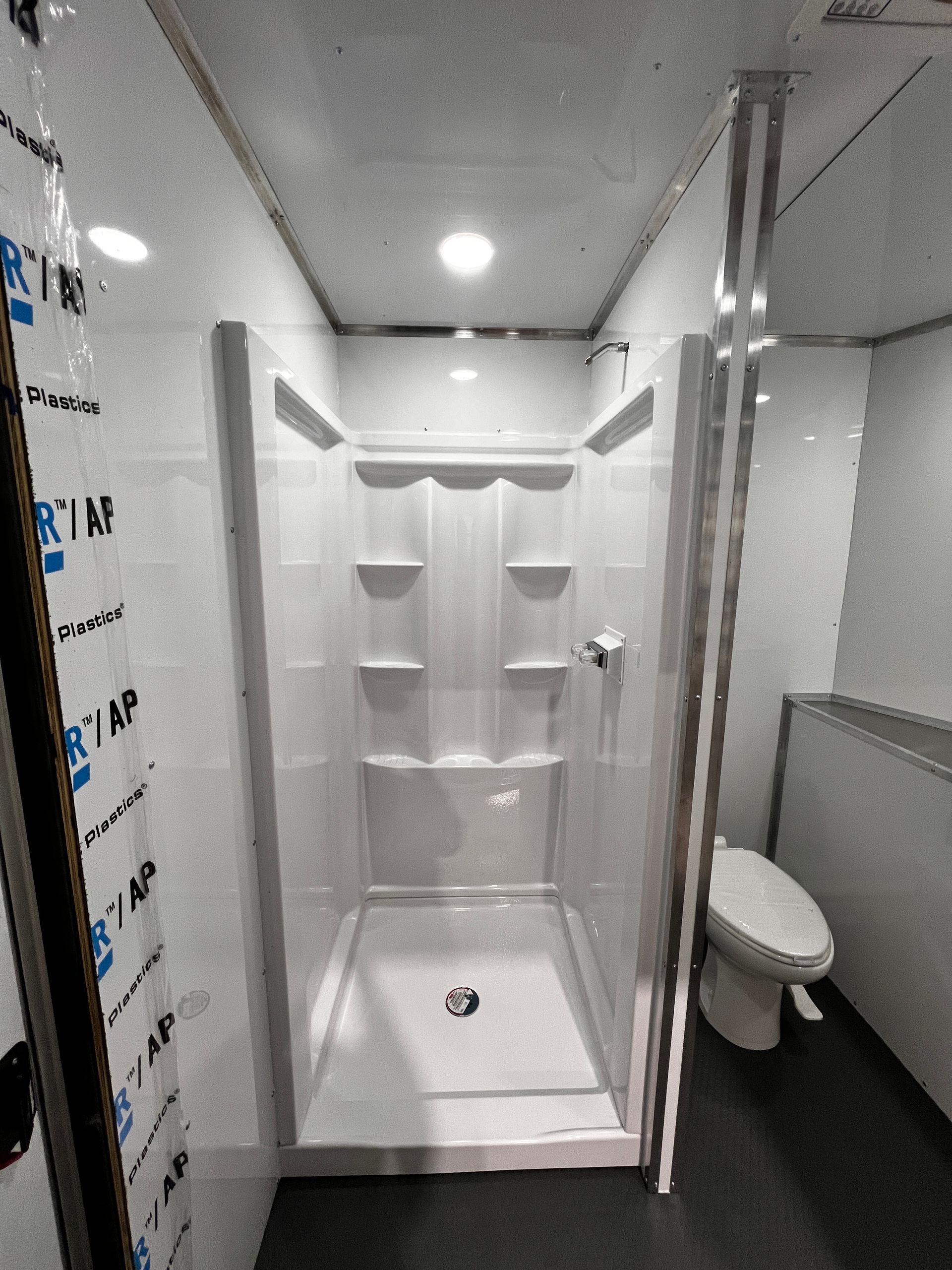 Modern shower stall with white walls, built-in shelves, and chrome fixtures in a bathroom