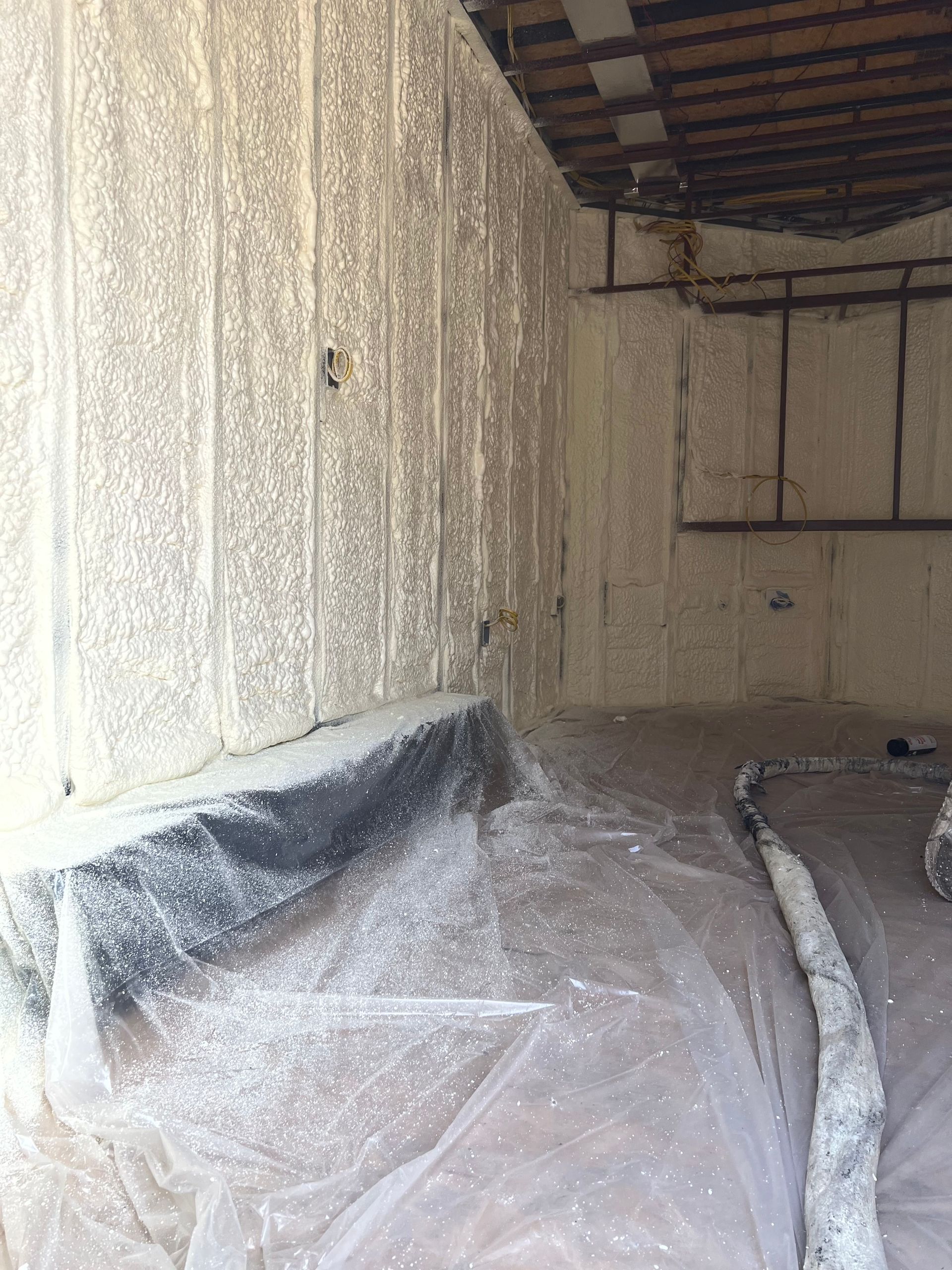 Interior of a long cargo truck trailer with white spray foam on walls and exposed roof beams