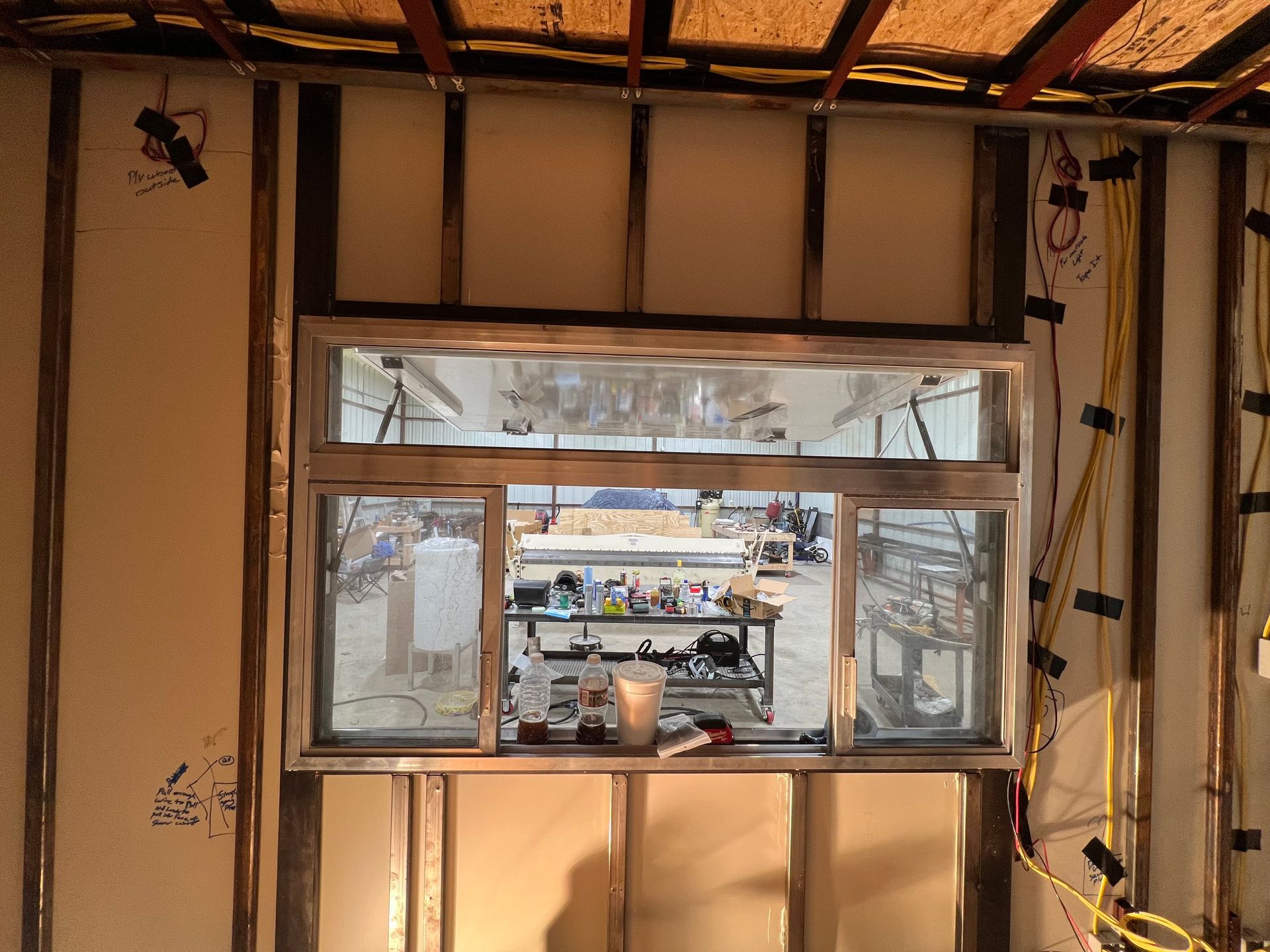 Interior of a long cargo truck trailer under upgrade renovation, exposed framing and a window overlooking a street scene.