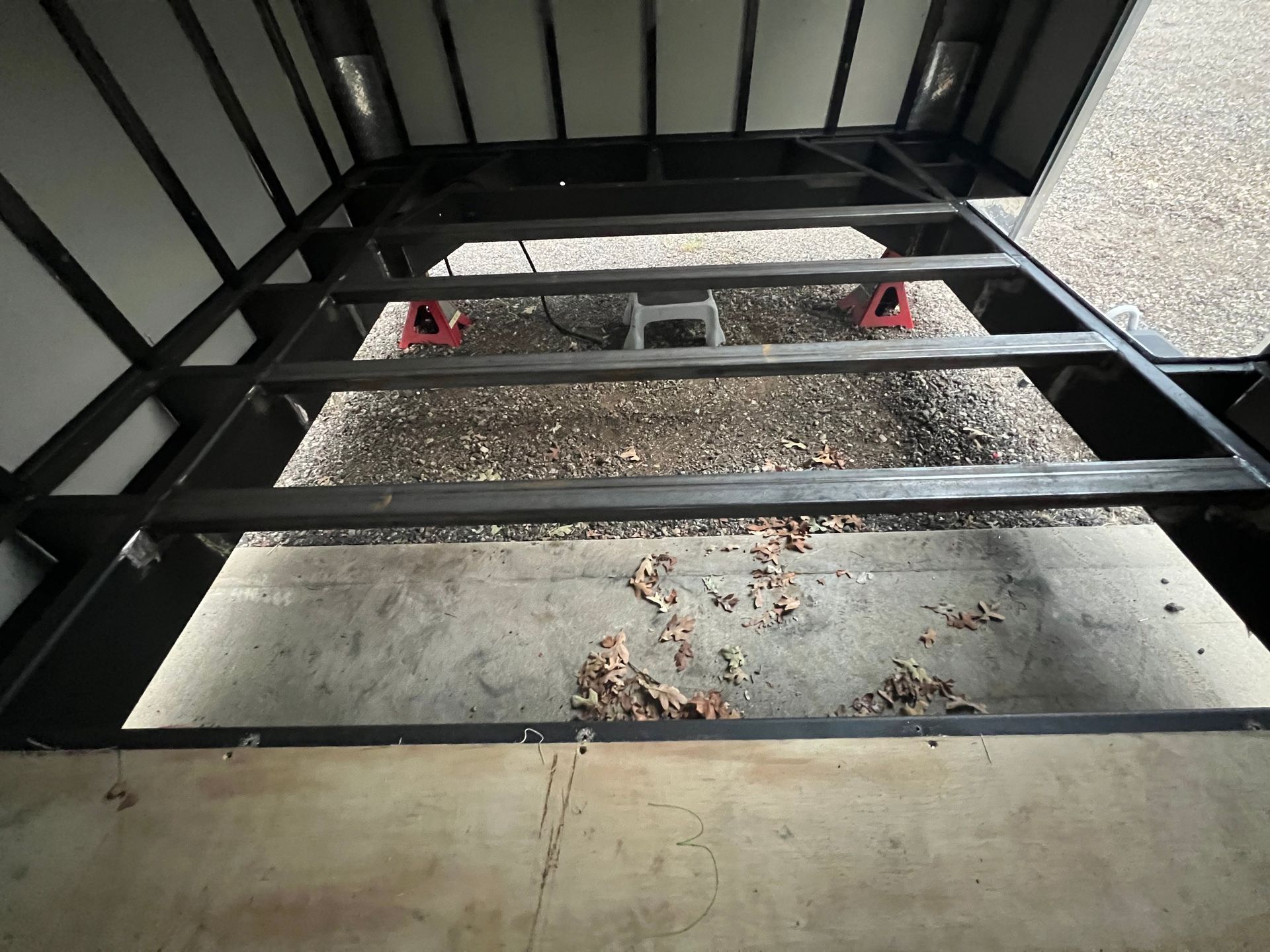 Frame of cargo trailer and wall panels during upgrade above a concrete floor.