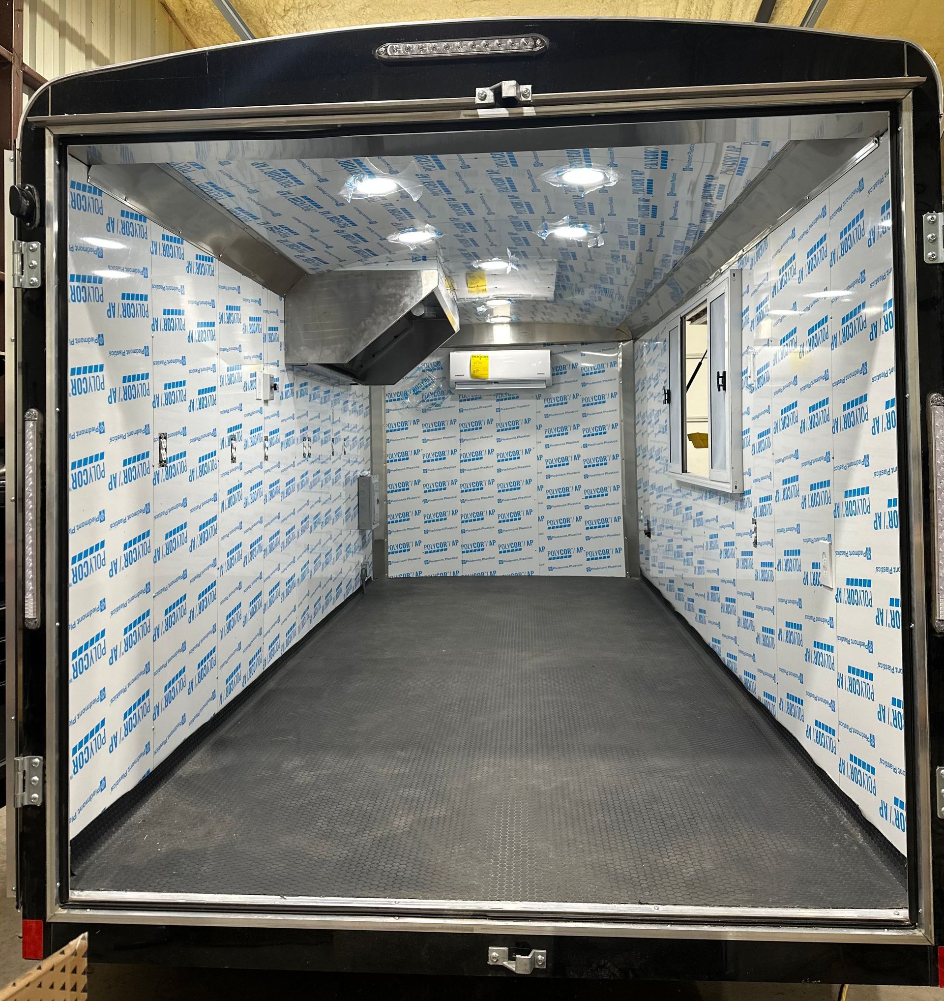 Empty insulated cargo trailer interior with black floor and white protective lining