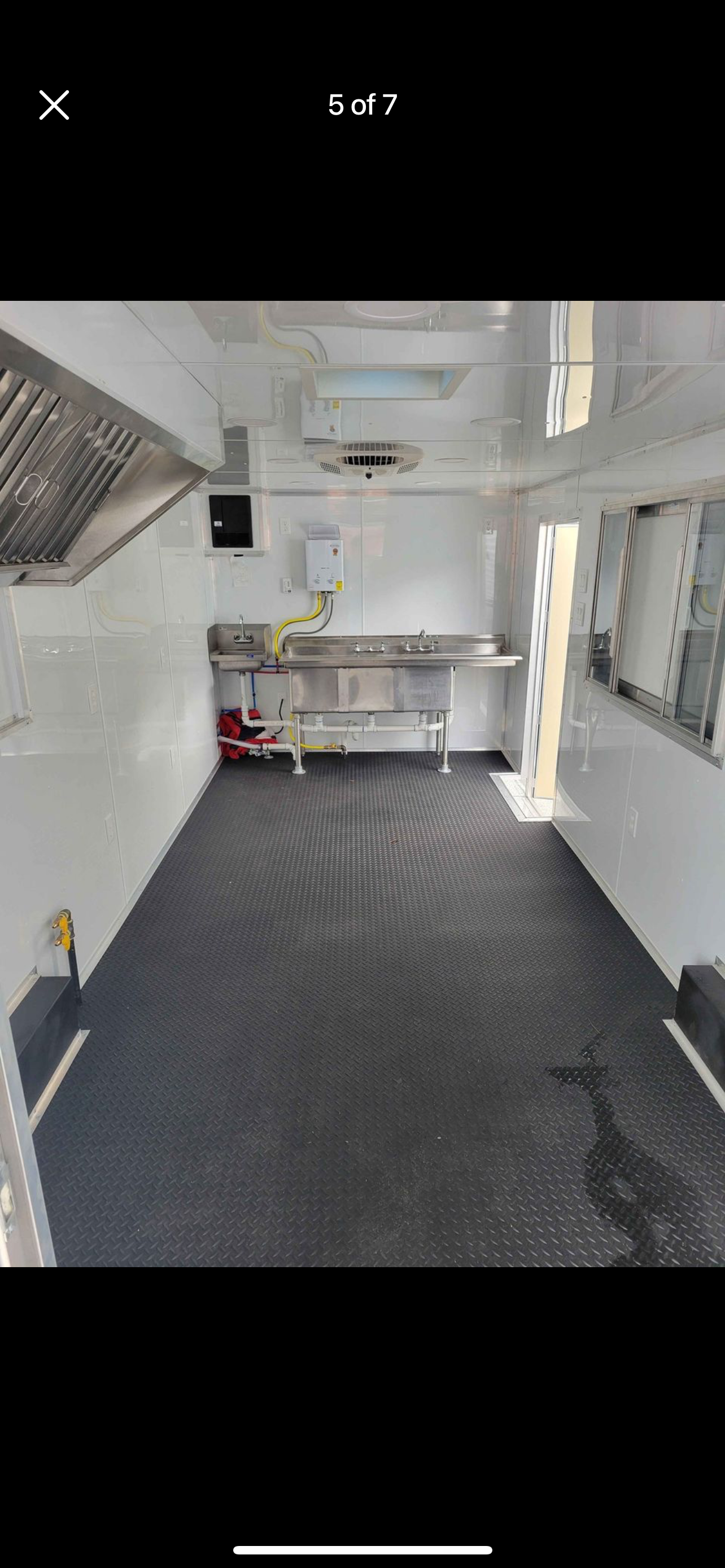 Empty white room with black diamond-pattern flooring and a stainless steel counter against the back wall