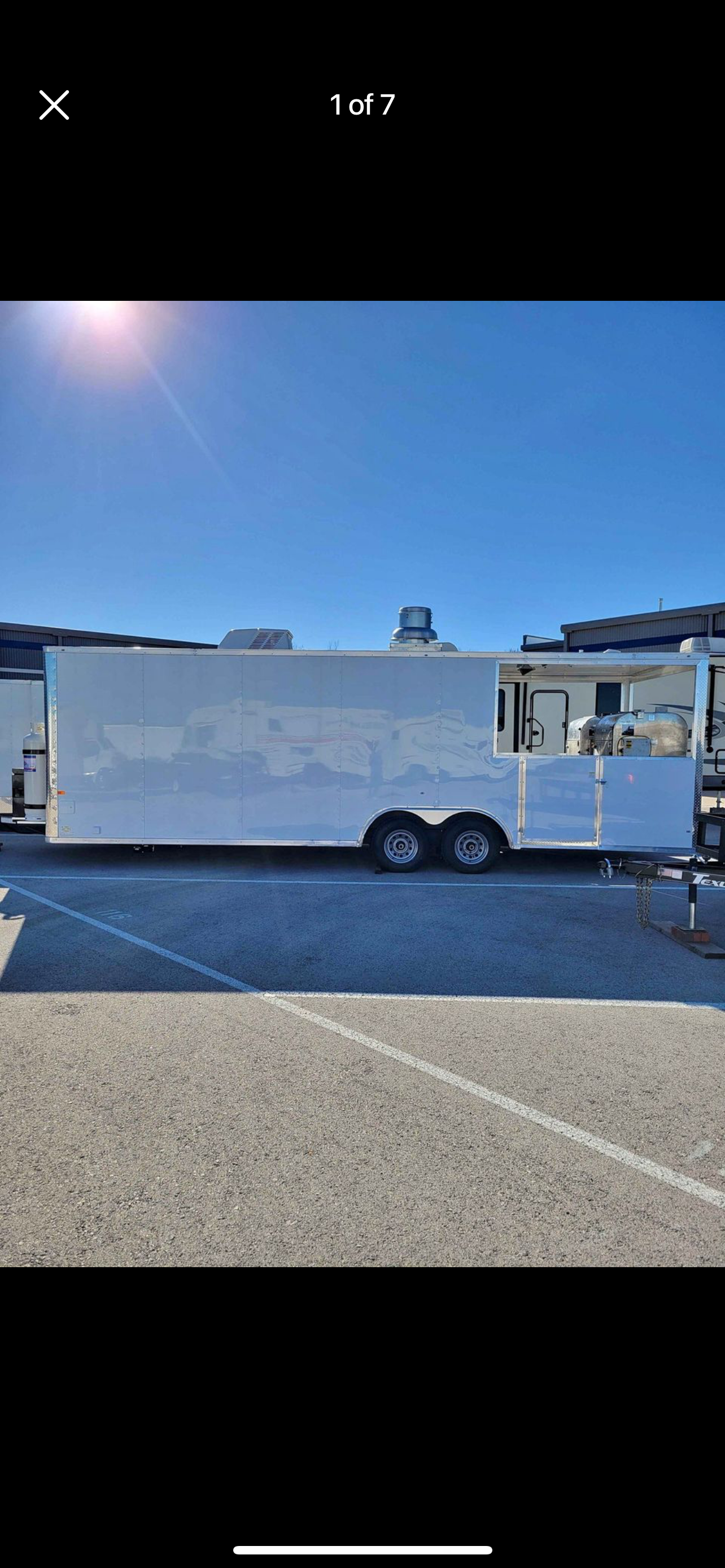 White box trailer parked on a sunny street under a blue sky