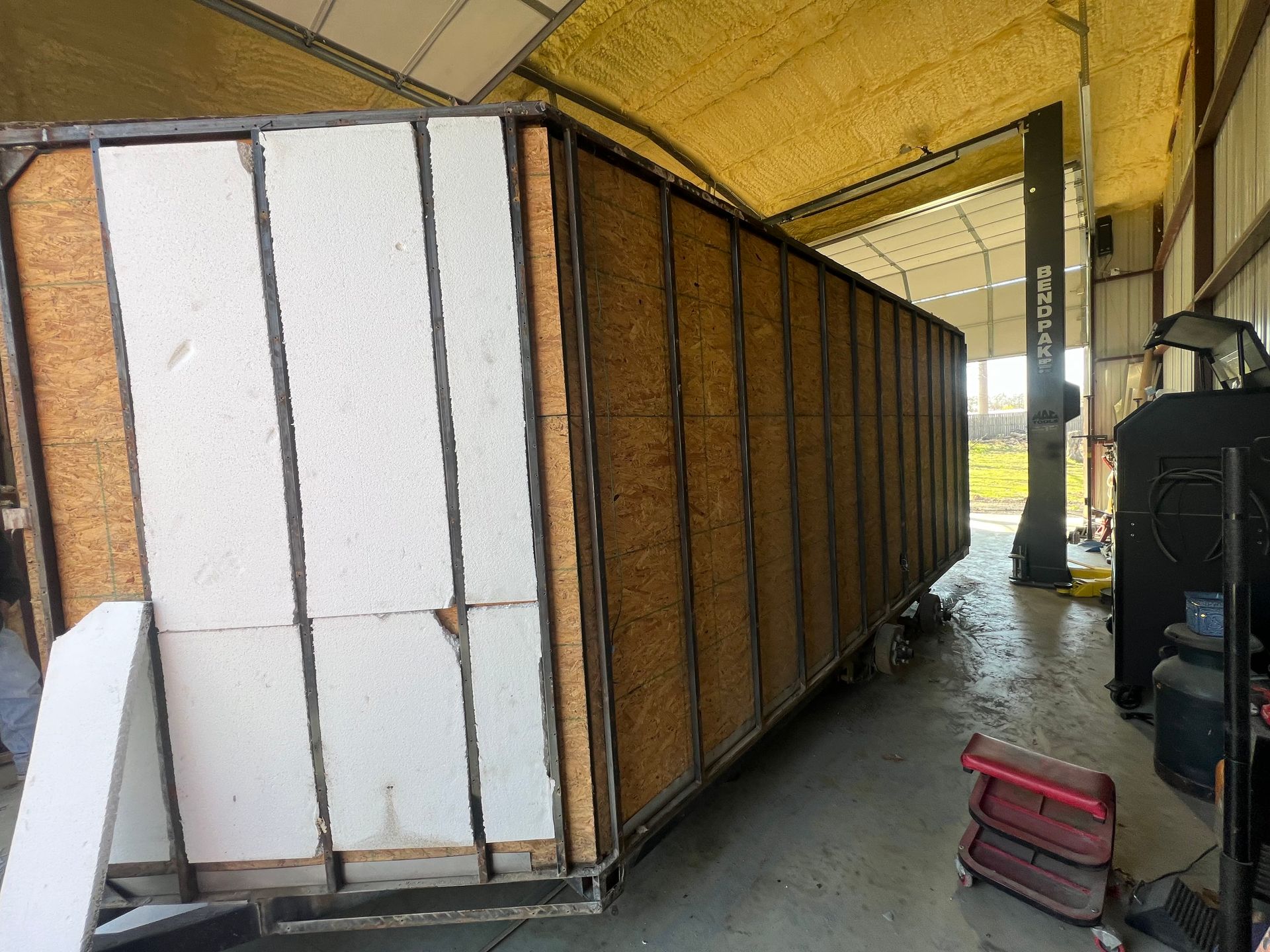 Large white-and-brown cargo trailer inside a covered industrial loading area