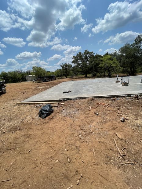 Black plastic ground grid laid over gravel beside a road, with stakes marking an installation area.