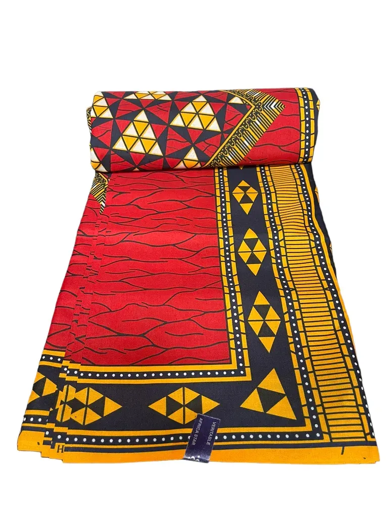 Colorful patterned woven mat folded into a stool-like shape, red with black, yellow, and white geometric designs