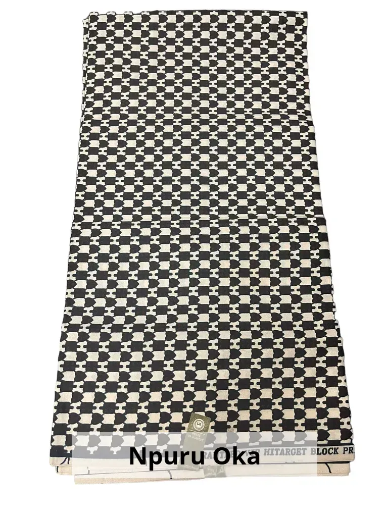 Patterned beige-and-black woven mat or rug laid out vertically, labeled “Npuru Oka” at the bottom.
