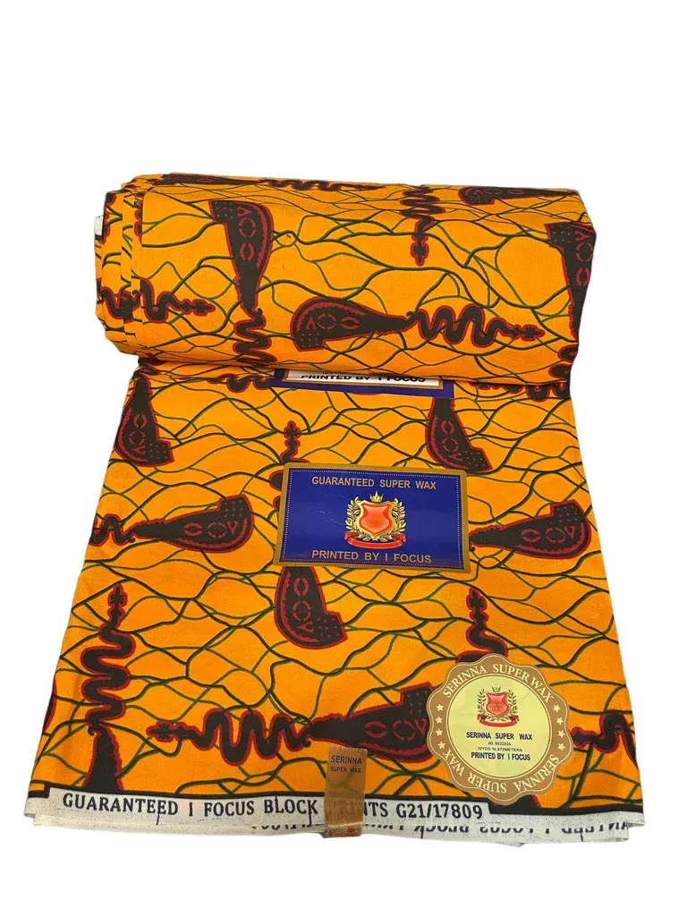 Orange patterned woven fabric with dark designs, folded and labeled with two tags.