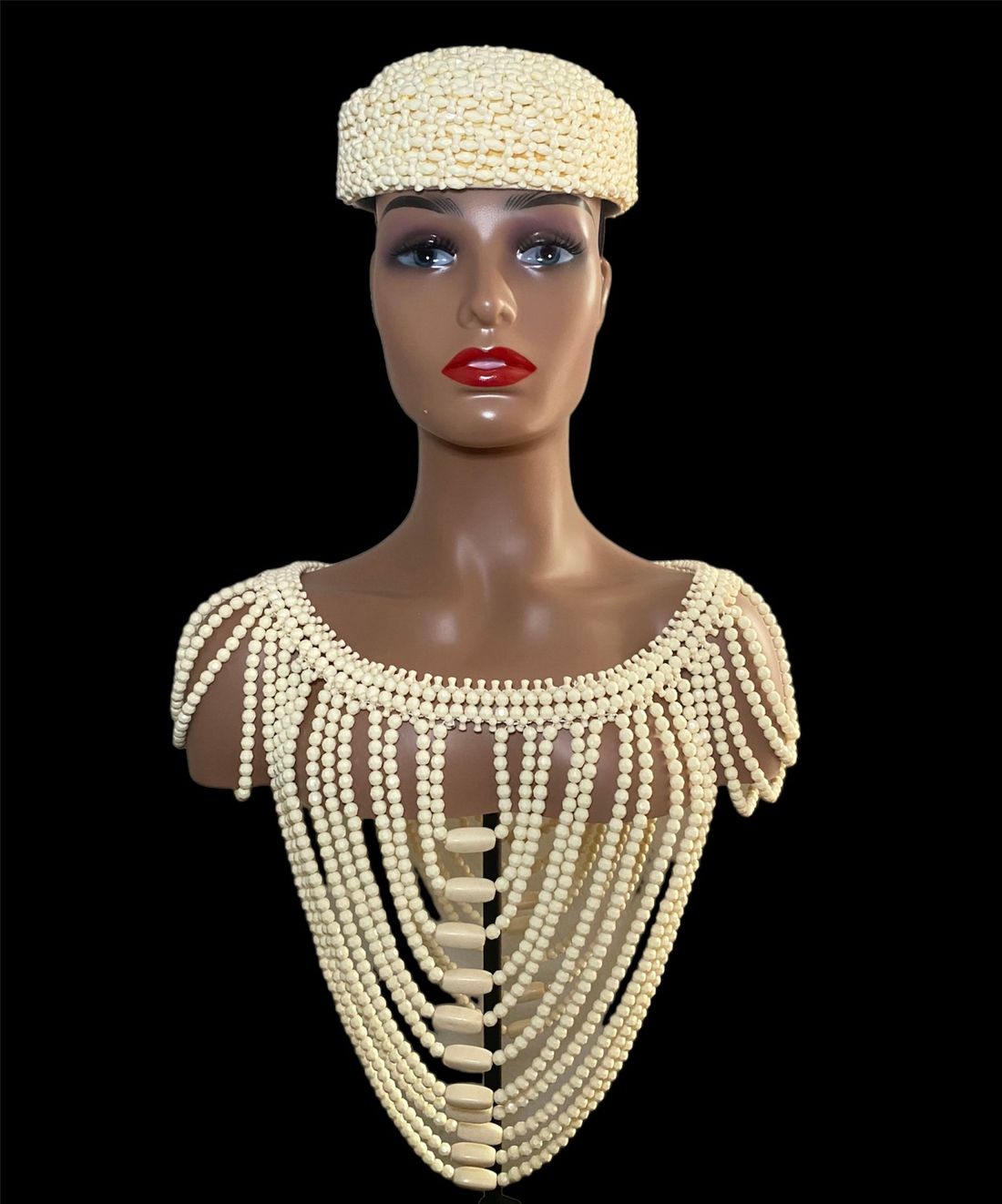 A mannequin wearing a hat and a necklace of pearls