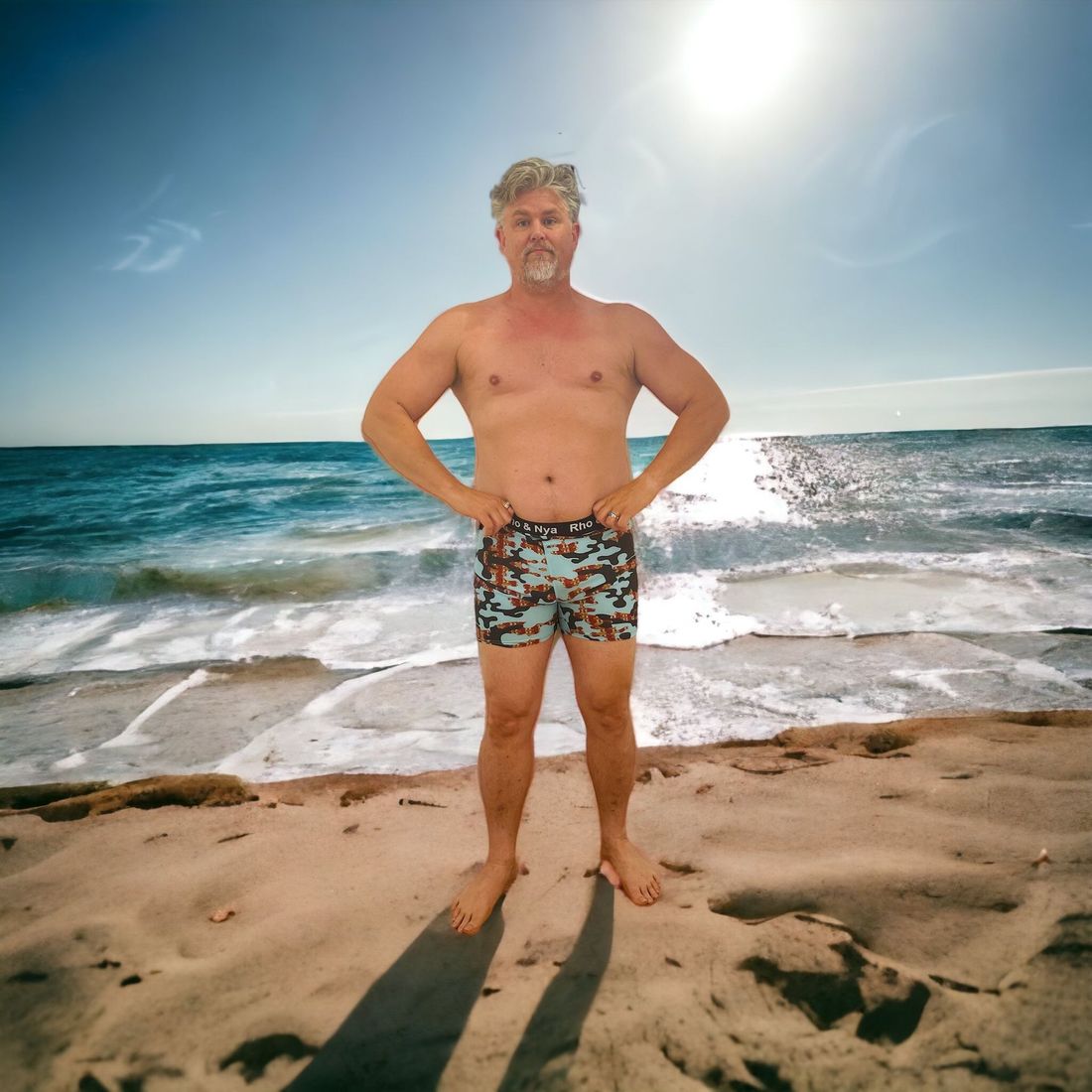 A shirtless man standing on a beach with his hands on his hips