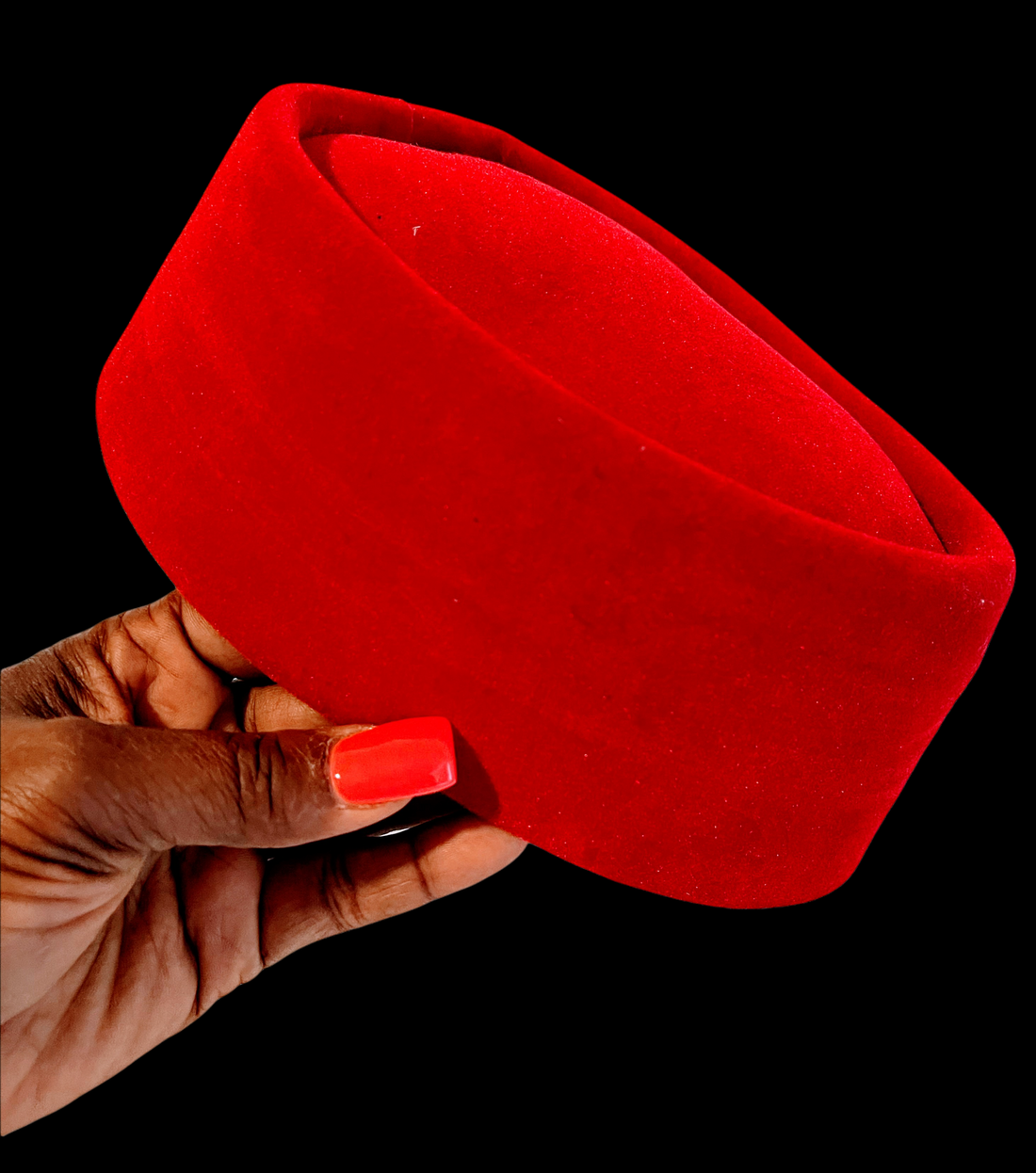 A woman 's hand with red nails is holding a red hat.