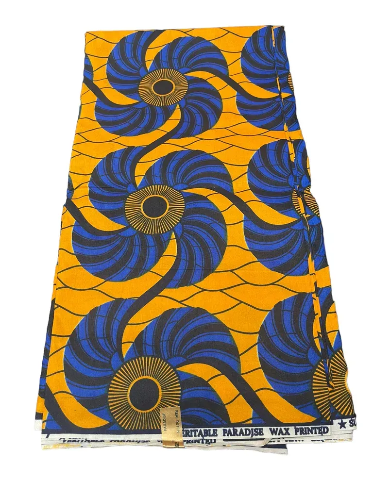 Orange fabric with bold blue spiral and black circular patterns, laid flat with a printed edge at the bottom