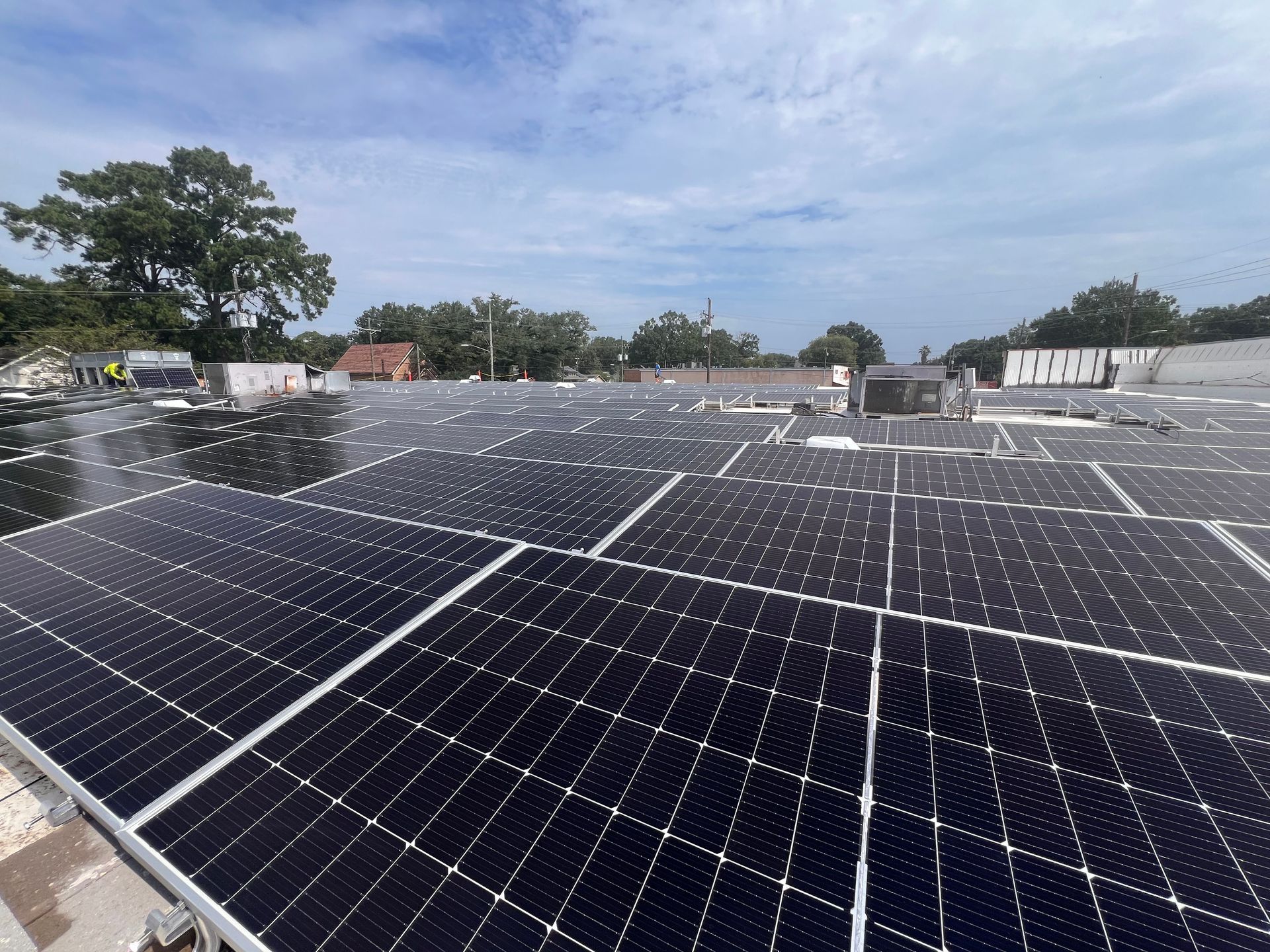 Rows of solar panels on a rooftop under a partly cloudy sky