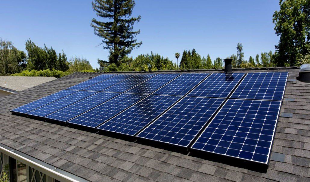 Solar panels on a sloped rooftop under a clear blue sky.