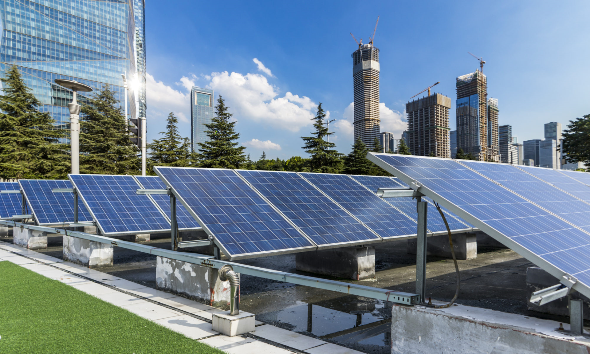 Solar panels on a rooftop with a city skyline and blue sky in the background