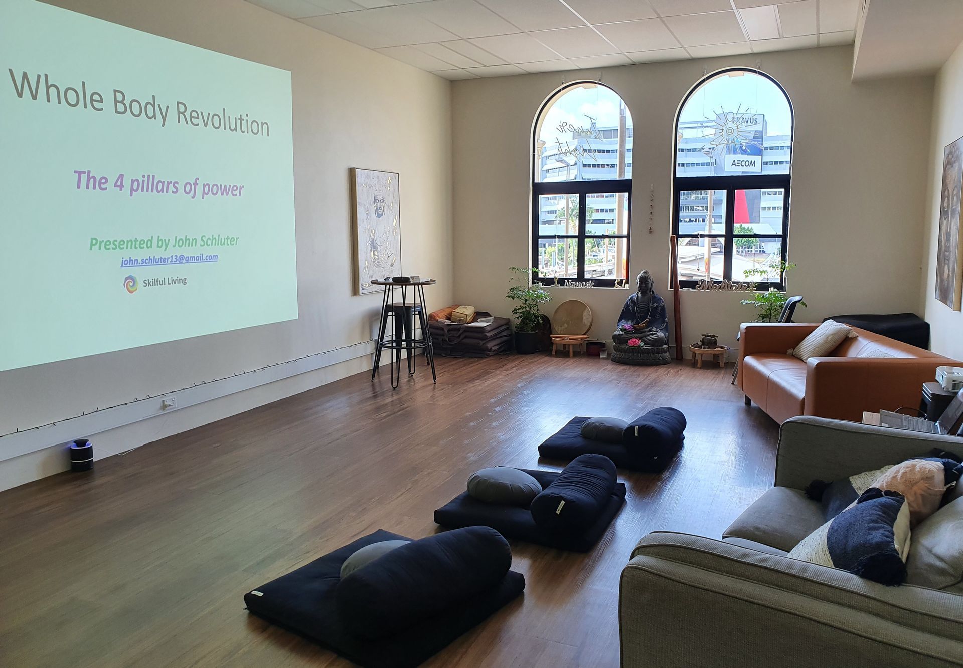 Yoga class in a bright living room with mats on the floor and a projected presentation on the wall