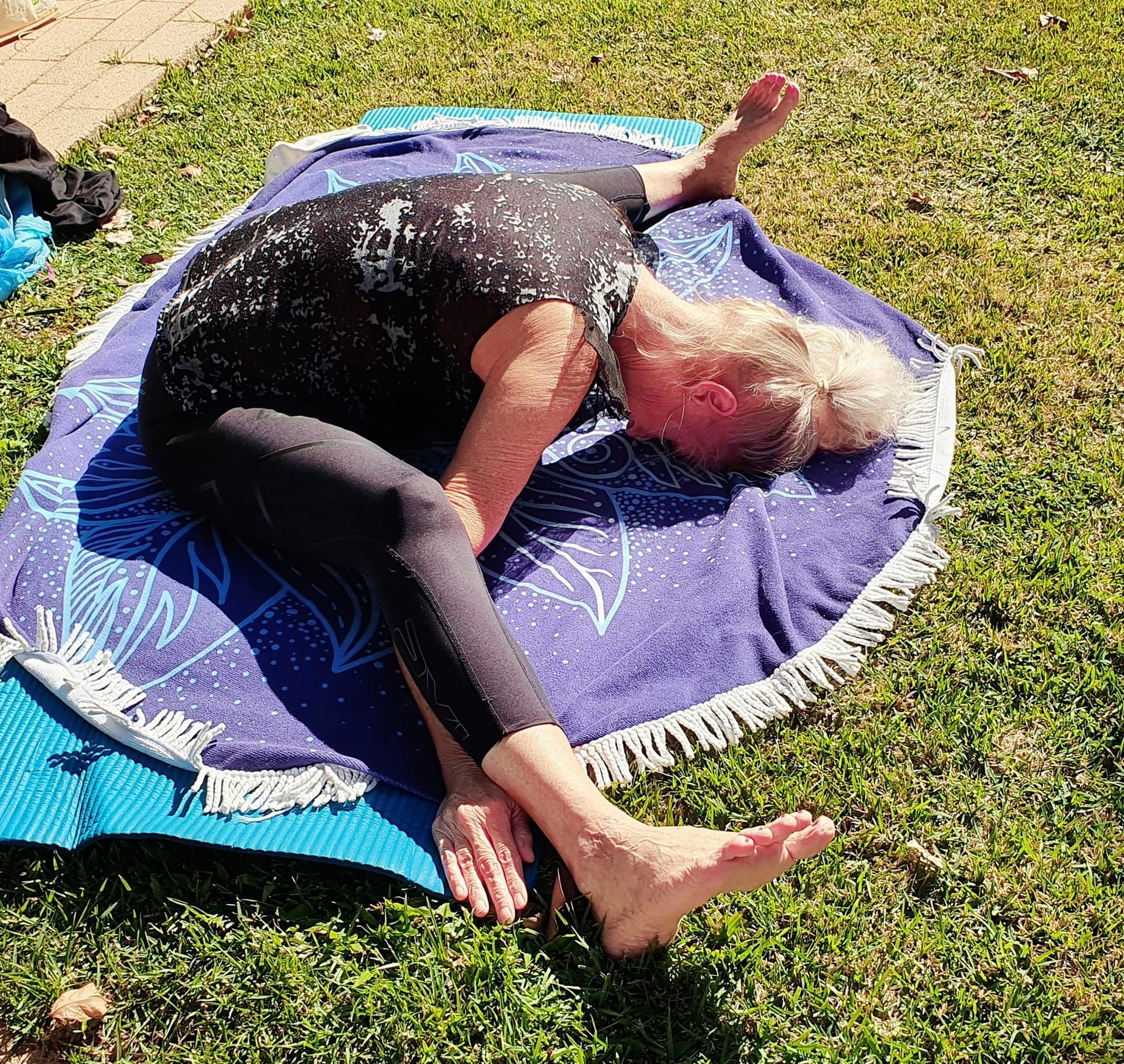 Person in Yoga Pose on a Blue Mat, Outdoors on Grass — Skilful Living in North Ward, QLD