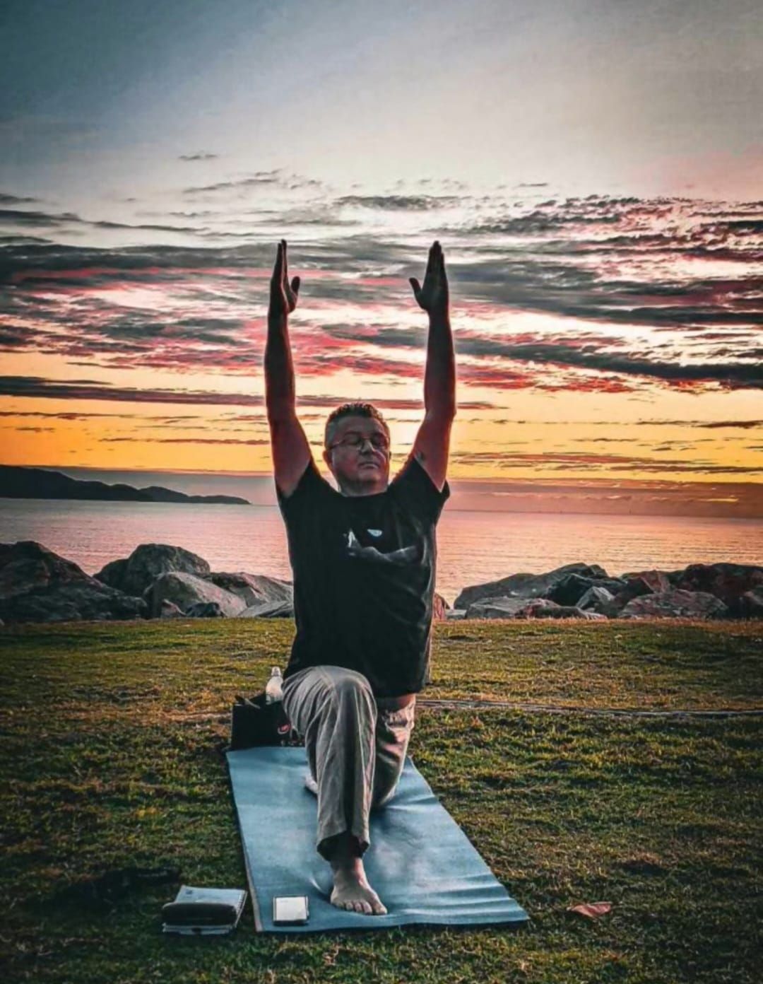 Man in Yoga Pose With Arms Raised; Sunset Over Water — Skilful Living in North Ward, QLD