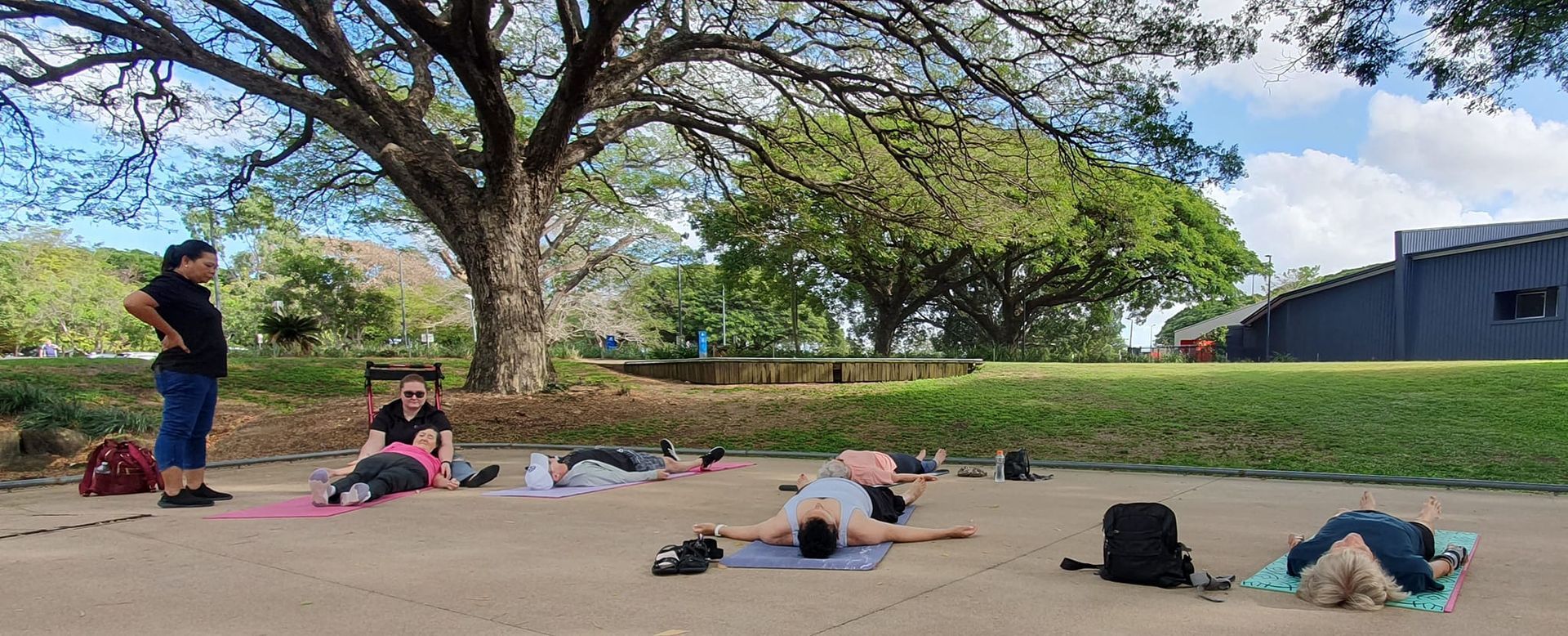 People Lying on Mats Under a Tree, With an Instructor Standing Nearby — Skilful Living in North Ward, QLD
