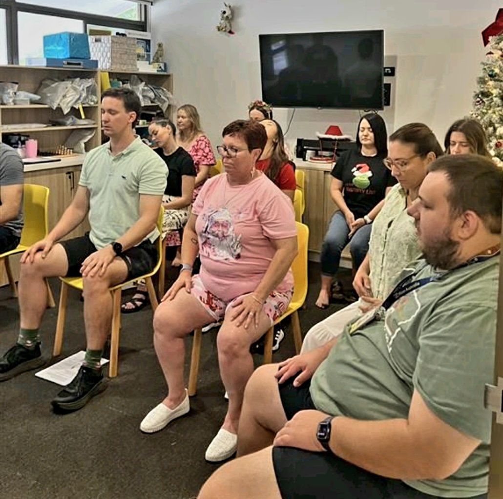 People seated in a room, facing forward in a group activity or meeting.