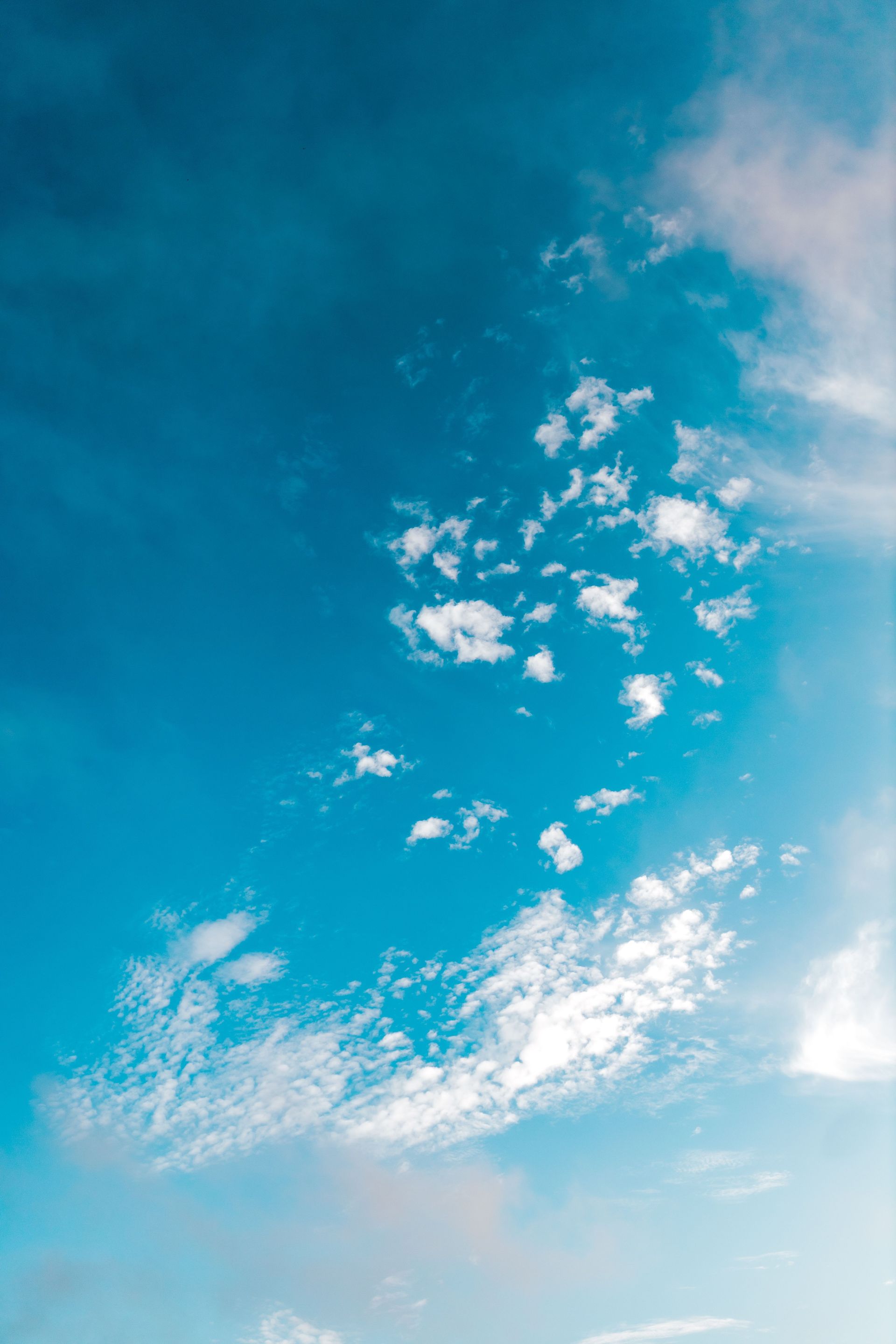 Bright blue sky with scattered white clouds and a faint sunlit glow near the horizon