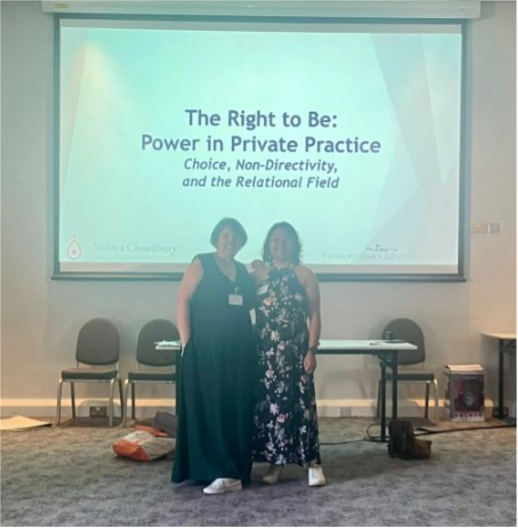 Two people standing on a stage before a presentation slide reading “The Right to Be”