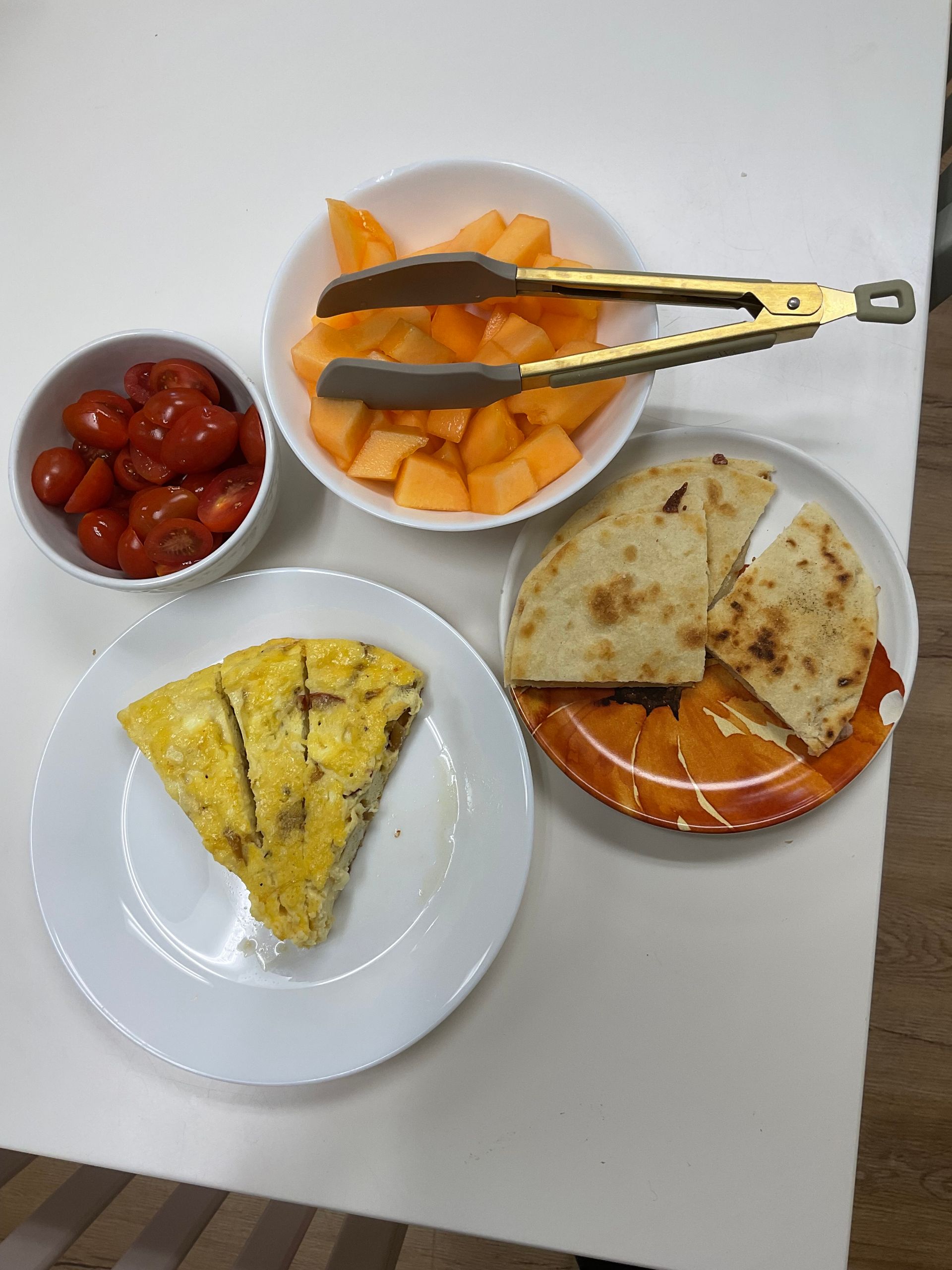 A table topped with plates of food and a bowl of fruit