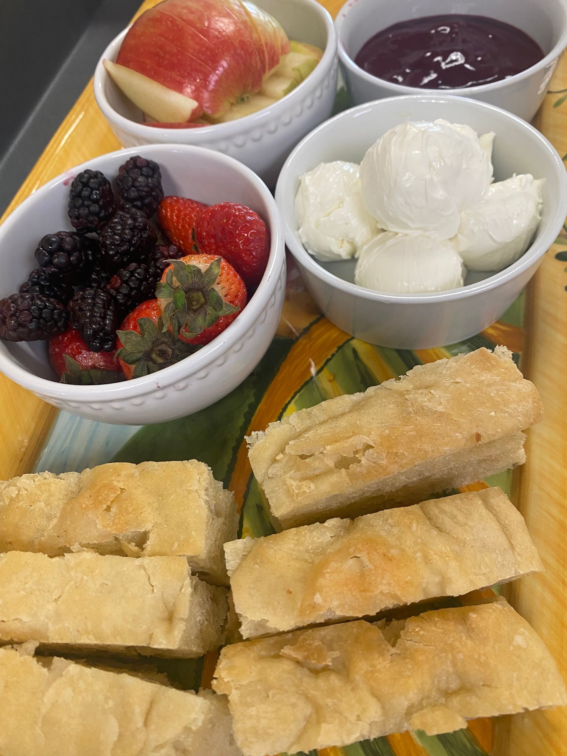 A tray of food with bread, fruit and sauces on it