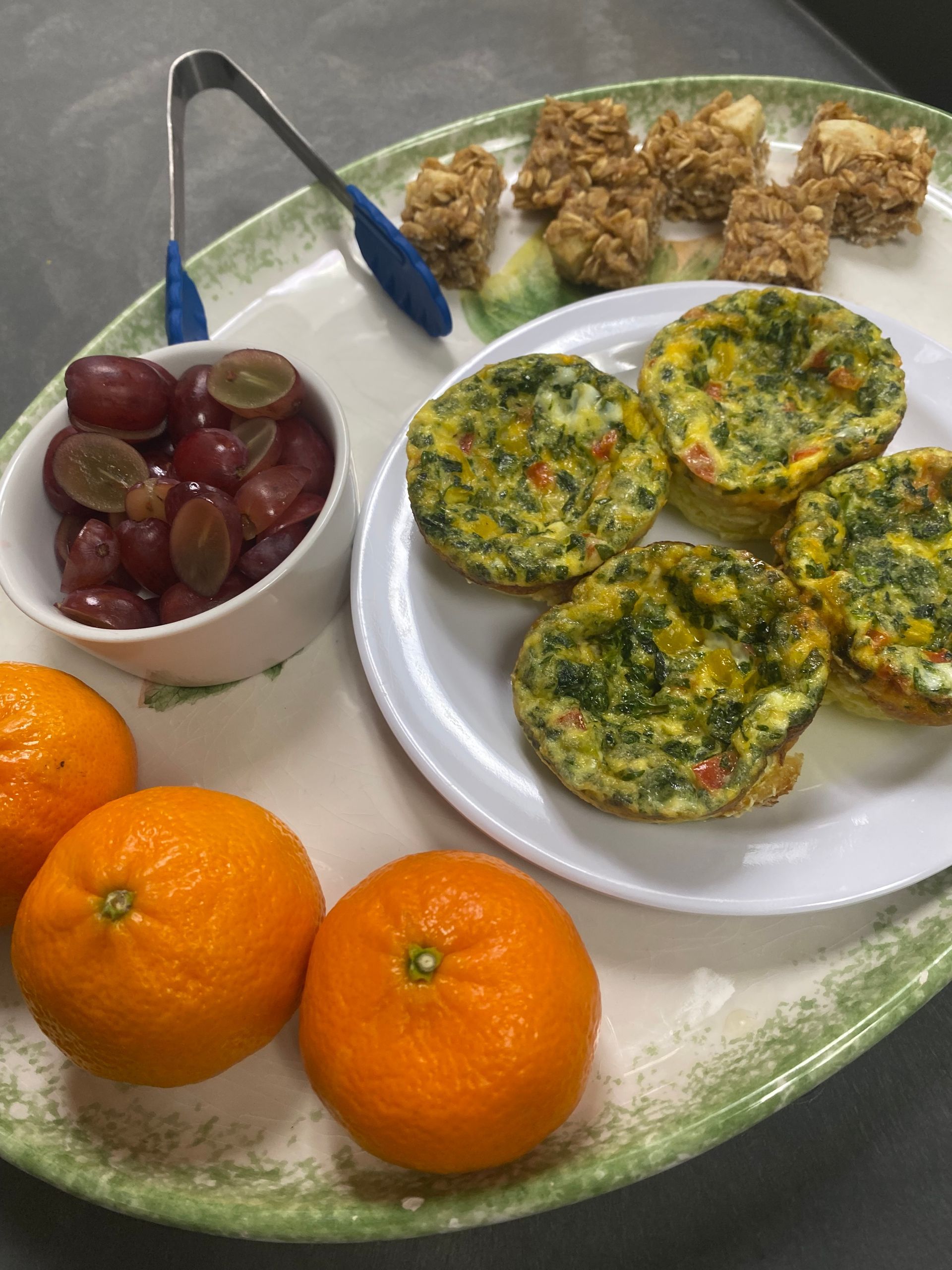 A plate of food with oranges and grapes on a tray