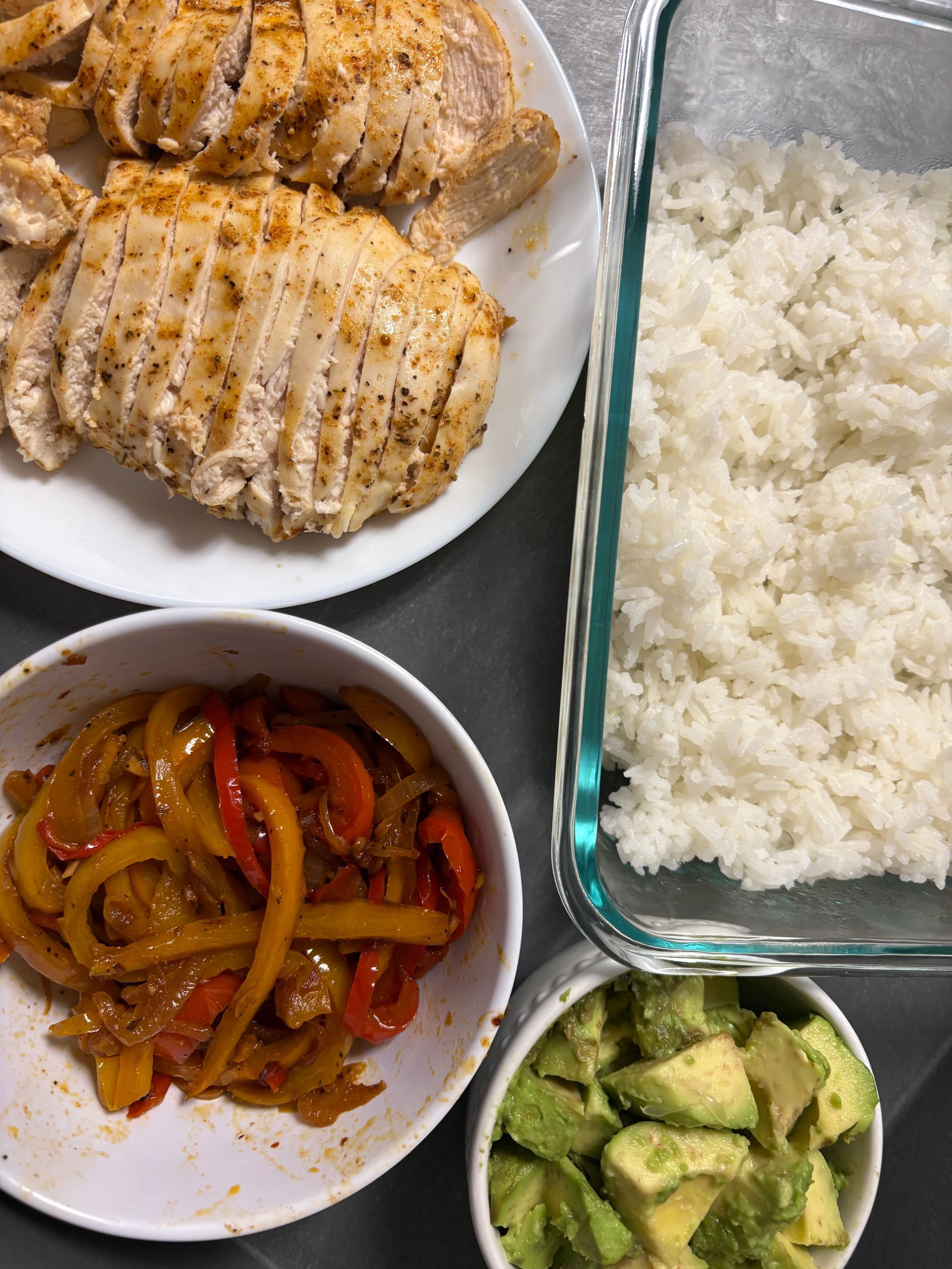 A bowl of avocado is next to a bowl of rice and a plate of chicken