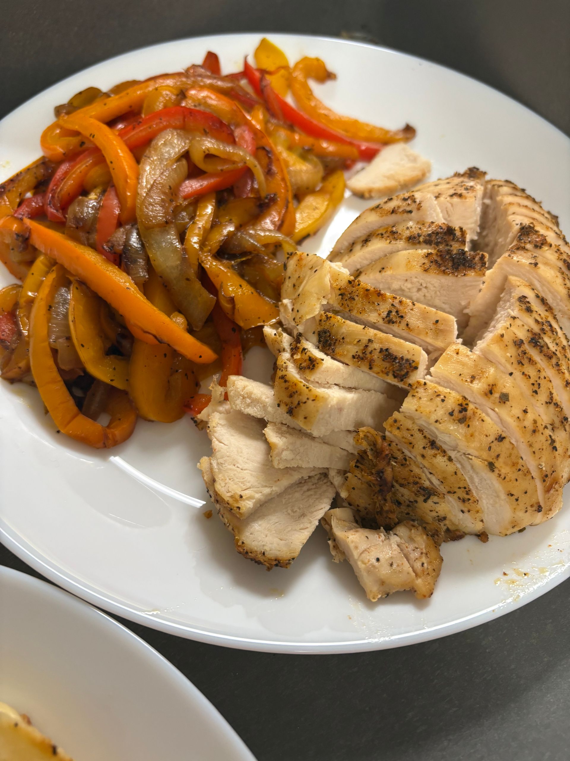 A white plate topped with sliced chicken and peppers
