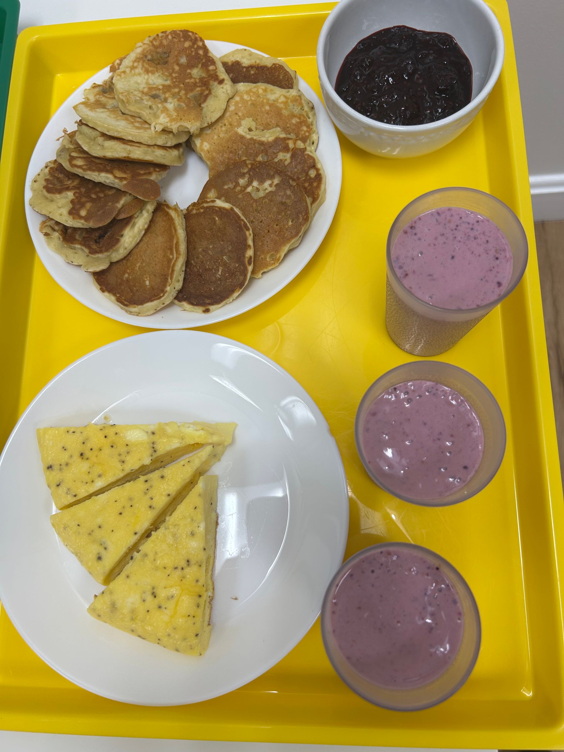 A yellow tray with pancakes and smoothies on it
