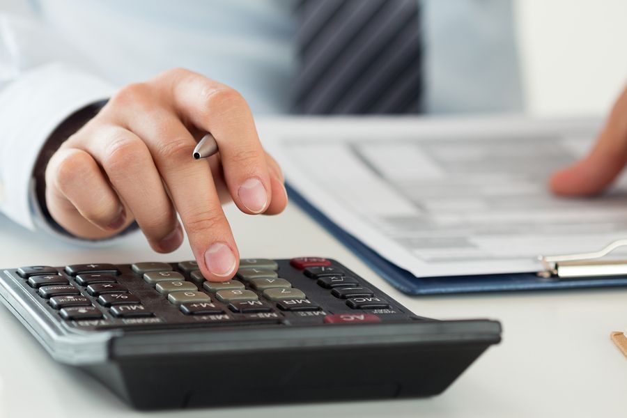 A person is using a calculator while holding a pen.
