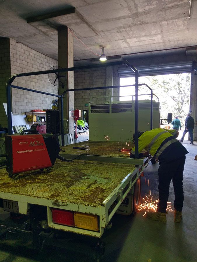 A Man Is Welding A Truck In A Garage — Wide Bay Hydraulics in Gympie, QLD