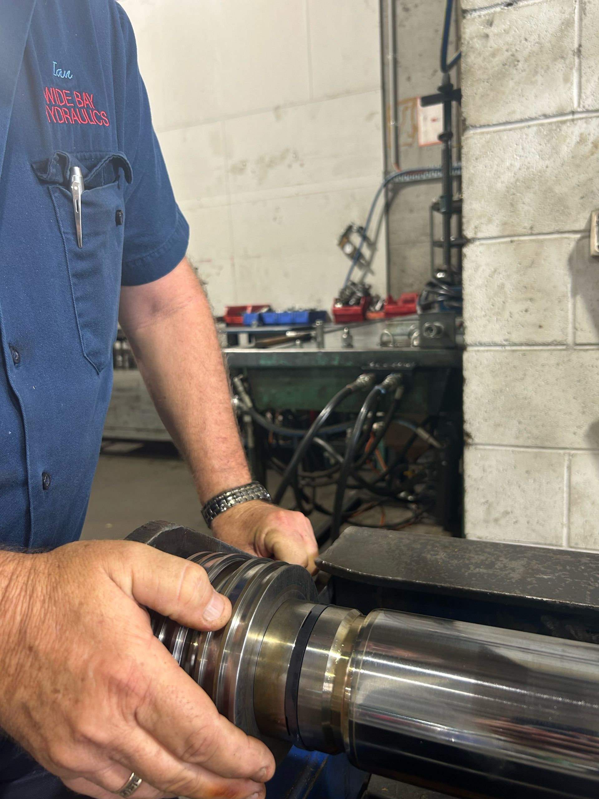 A Man Is Working On A Hydraulic Machine — Wide Bay Hydraulics in Gympie, QLD