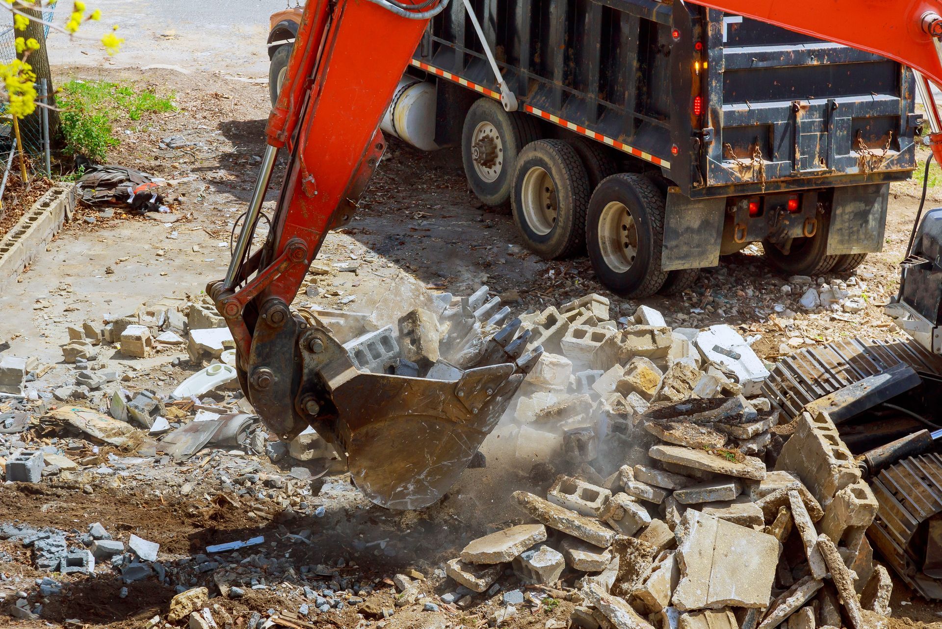 An excavator loads debris into a dump truck on a construction site.
