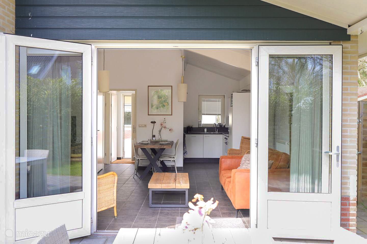 Een woonkamer met een bank, tafel, stoelen en glazen schuifdeuren.