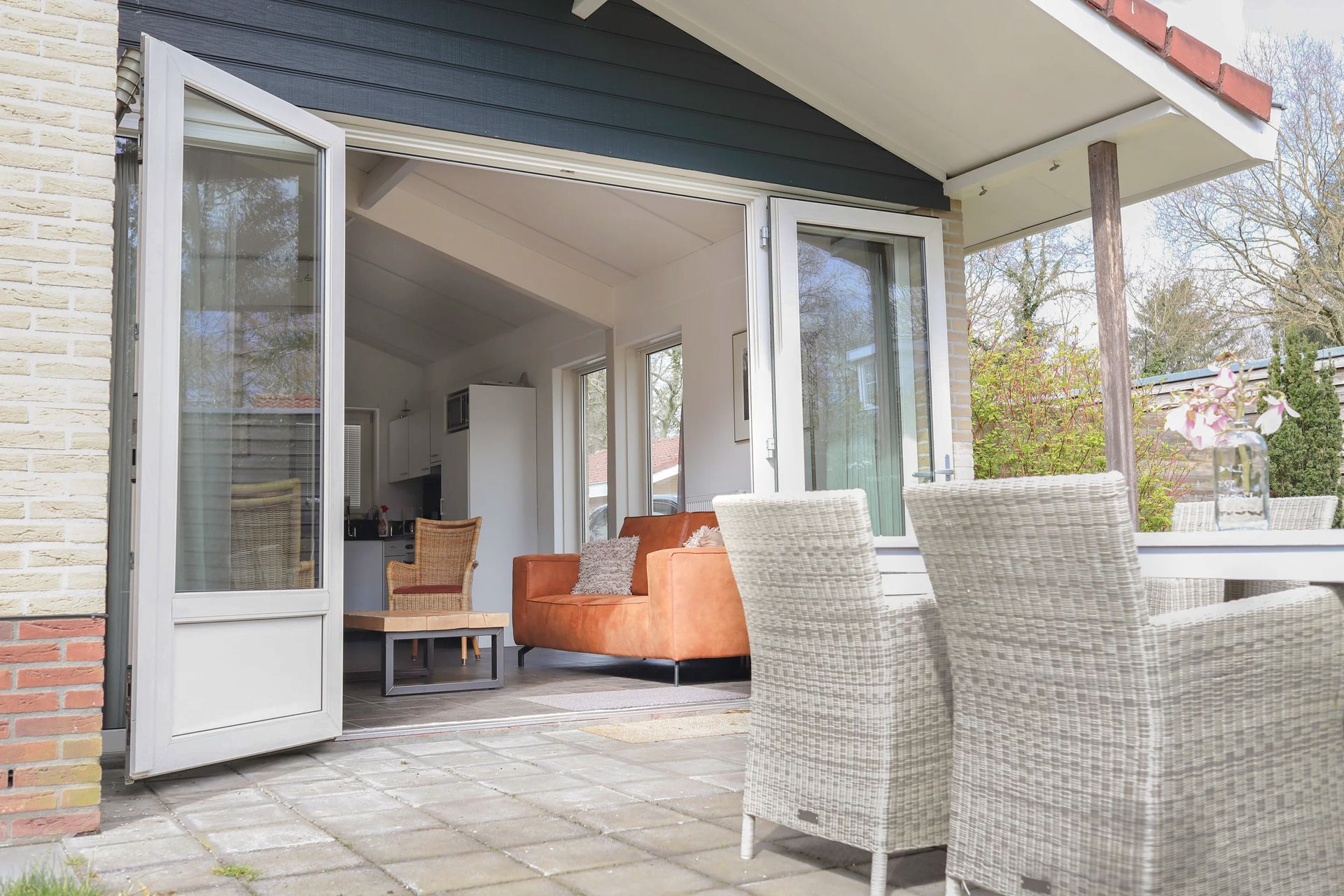 Een terras met rieten stoelen en een tafel voor een huis.