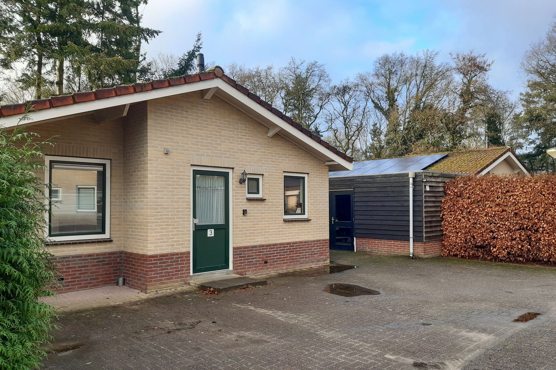 Een klein bakstenen huis met een groene deur en ramen