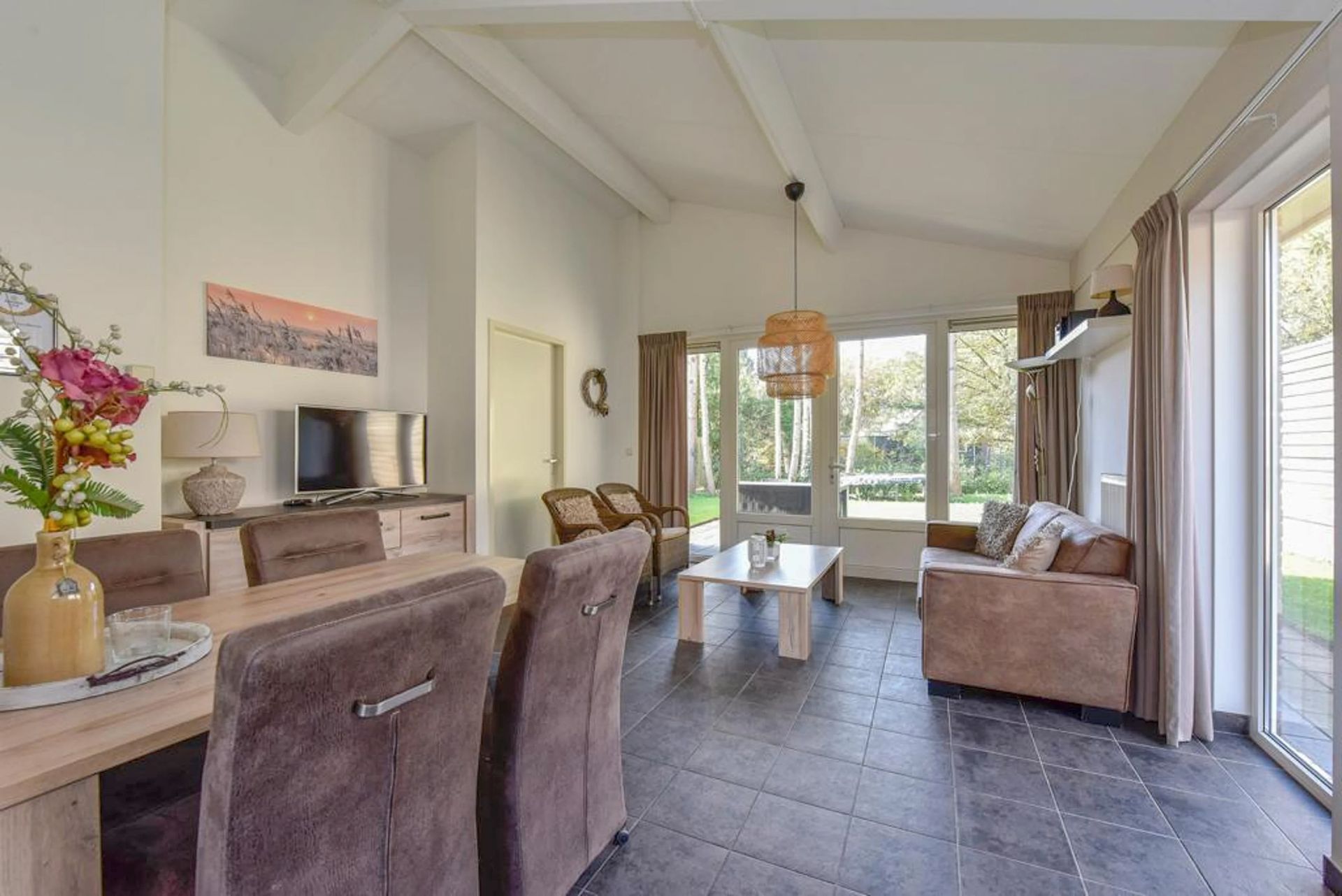 Een woonkamer met een tafel, stoelen, bank, salontafel en televisie.