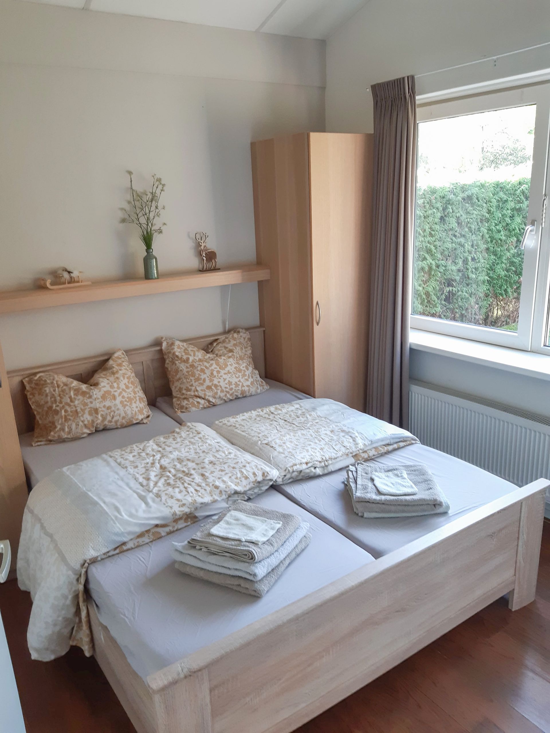 Een slaapkamer met twee bedden, een raam en een kledingkast.